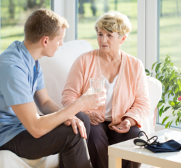 caregiver serving a glass of water for elder woman