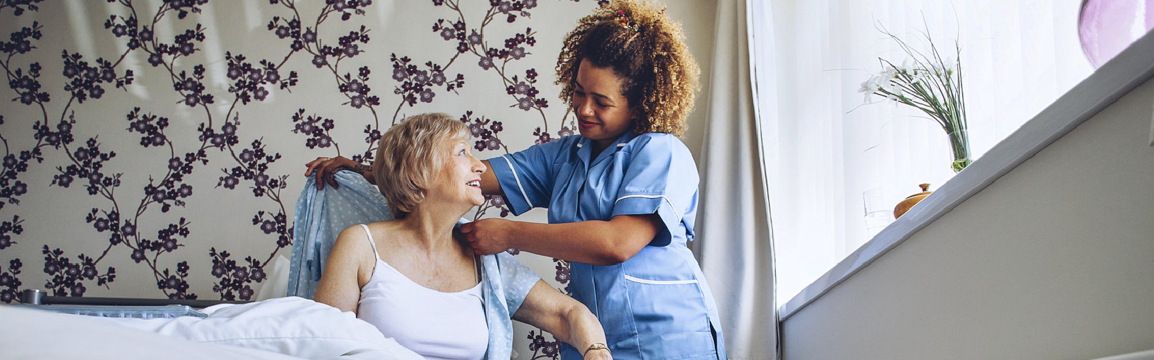 caregiver helping elder woman get dressed