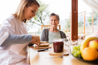 caregiver preparing a breakfast to senior woman