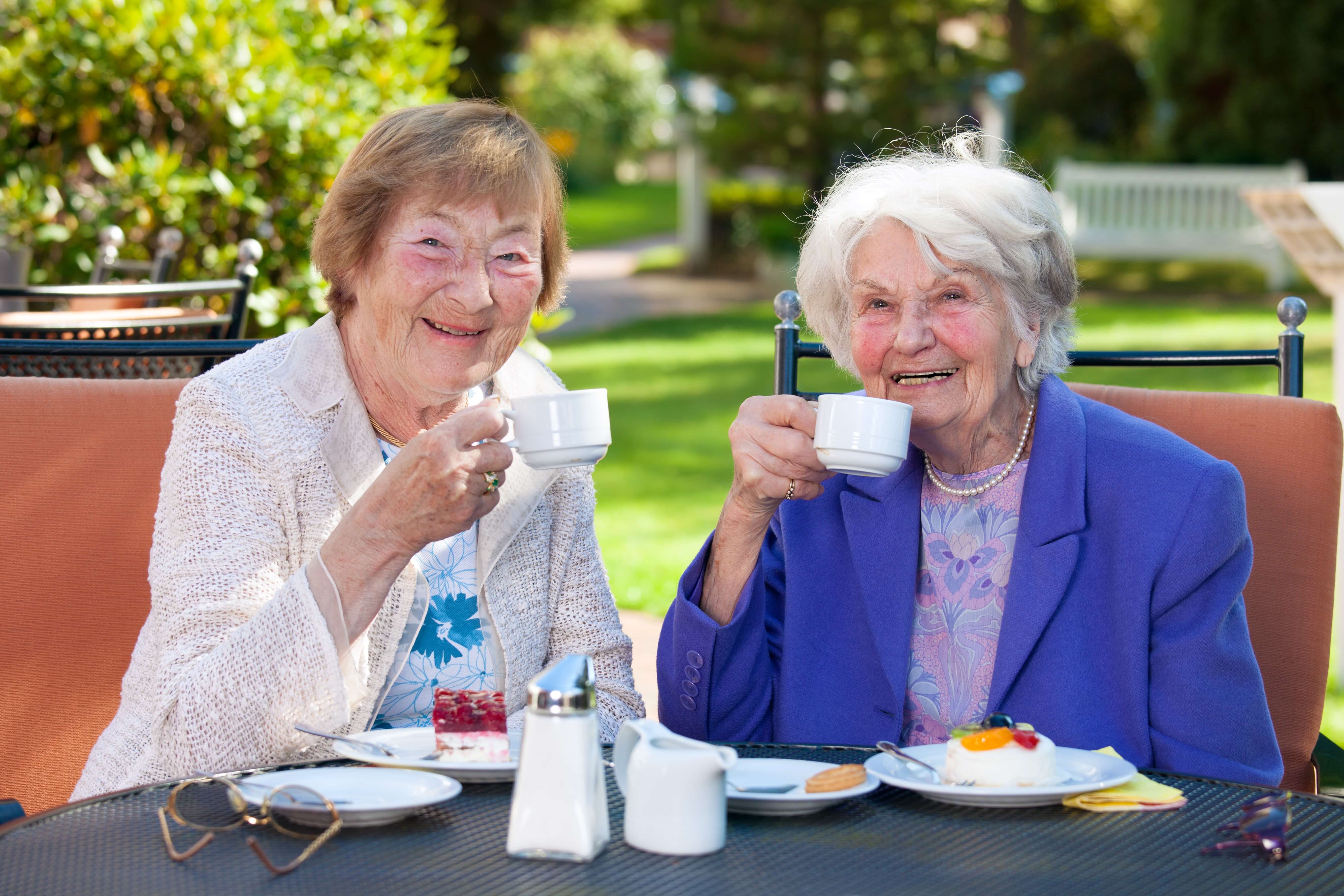 two senior women holding a cup