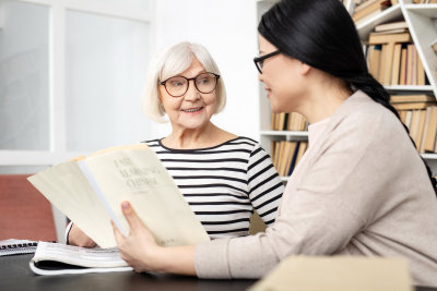 Tutor carrying book while jolly senior woman smiling